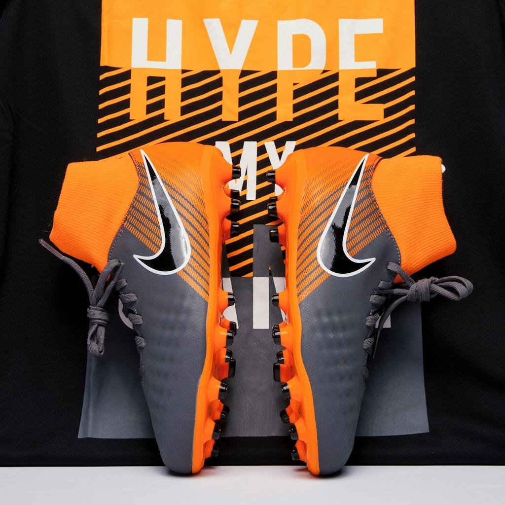 Close-up of gray and orange soccer cleats displayed against a bold background, ideal for fashion and sports enthusiasts.