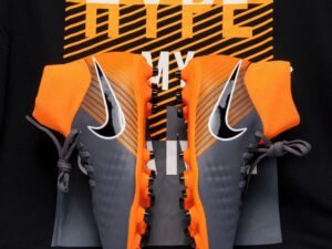 Close-up of gray and orange soccer cleats displayed against a bold background, ideal for fashion and sports enthusiasts.